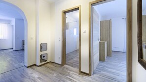 Una habitación amplia con piso de madera, un espejo grande y una puerta que da a otra habitación.
