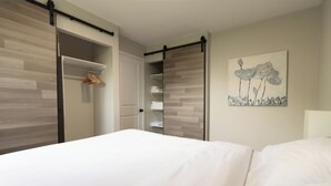A bedroom with a bed, a sliding closet, and a wall-mounted artwork.
