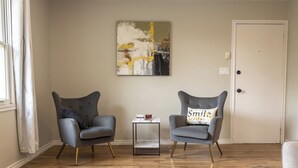 A room with two grey armchairs, a small table, and a wall art piece.