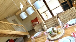 A dining area with a wooden table set for four, surrounded by wicker chairs. - Holiday Home Goldstuck (Oberharz am Brocken)