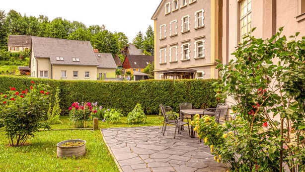 A courtyard with a stone patio, outdoor seating, and a hedge. - Eindverdieping DG (Sebnitz)