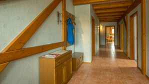 A hallway with wooden beams, a tiled floor, and a bench. - Eindverdieping DG (Sebnitz)