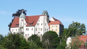 A large, historic building with multiple towers and a red roof, surrounded by trees. - Eindverdieping DG (Sebnitz)