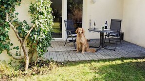 A patio with a dog, a table, and chairs. - Beachkeeper Comfortable Holiday Residence (Zingst)