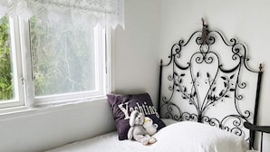 A bedroom with a single bed, a window with lace curtains, a decorative metal headboard, and a bedside lamp. - 5 Person Holiday Home in Djurhamn (Djurhamn)
