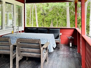 A covered outdoor seating area with a table and chairs, a hanging light fixture, and a view of a forested area. - 5 Person Holiday Home in Djurhamn (Djurhamn)