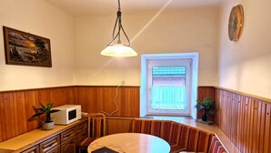 Een gezellige keuken met houten lambrisering, een eettafel, een magnetron en een raam met uitzicht.