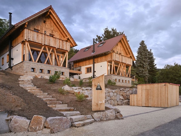 Un chalet de madera con una escalera de piedra que lleva a una terraza de madera.