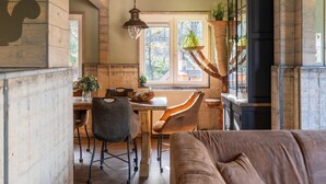 Une cuisine rustique aux murs en bois, une table à manger avec des chaises, un luminaire suspendu et un arbre à chat.