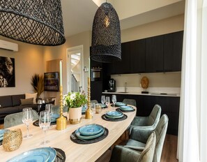 A modern dining area with a long wooden table set for six, featuring blue plates and gold accents. - Farm Villa Wellness (Wekerom)