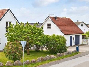 A row of white houses with red roofs, a clear sky, and a well-maintained lawn. - 4 Star Holiday Home in Ahus (Aahus)