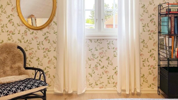 A room with a window, a mirror, a chair, a bookshelf, and floral wallpaper. - 4 Star Holiday Home in Ahus (Aahus)