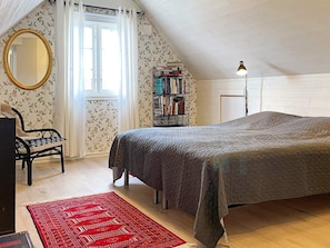 A bedroom with a bed, a chair, a bookshelf, and a window with curtains. - 4 Star Holiday Home in Ahus (Aahus)