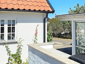 A house with a tiled roof, a window, and a garden with plants and a small water feature. - 4 Star Holiday Home in Ahus (Aahus)