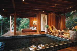 Una terraza de madera con un jacuzzi, dos cuencos metálicos y una silla.