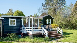 Een klein huisje met een terras, een overdekte veranda en een trap naar de ingang.