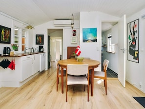 A modern kitchen with white cabinets, a wooden dining table, and a flag. - 8 Person Holiday Home in Holbaek (Holbaek)
