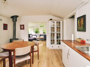 A cozy interior with a dining area, a kitchen with a built-in stove, and a view into a dining room. - 8 Person Holiday Home in Holbaek (Holbaek)