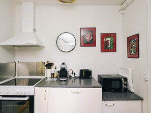 A kitchen with a stove, microwave, coffee maker, and a clock on the wall. - 8 Person Holiday Home in Holbaek (Holbaek)