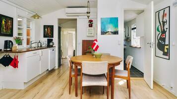 A modern kitchen with white cabinets, a wooden dining table, and a flag on the wall.