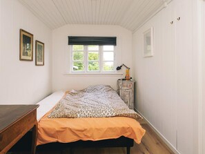 A bedroom with a bed, a desk, a window with a view, and a lamp on a dresser. - 8 Person Holiday Home in Holbaek (Holbaek)