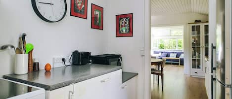 A kitchen with a clock, a toaster, and a stove. There are cabinets and a countertop.