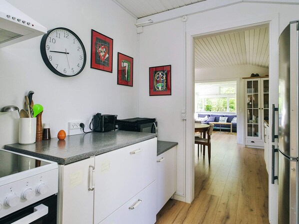 A kitchen with a clock, a toaster, and a stove. There are cabinets and a countertop.