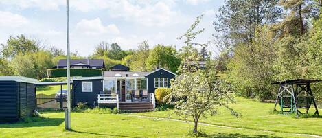 A residential property with a large lawn, a wooden deck, and a small garden area.