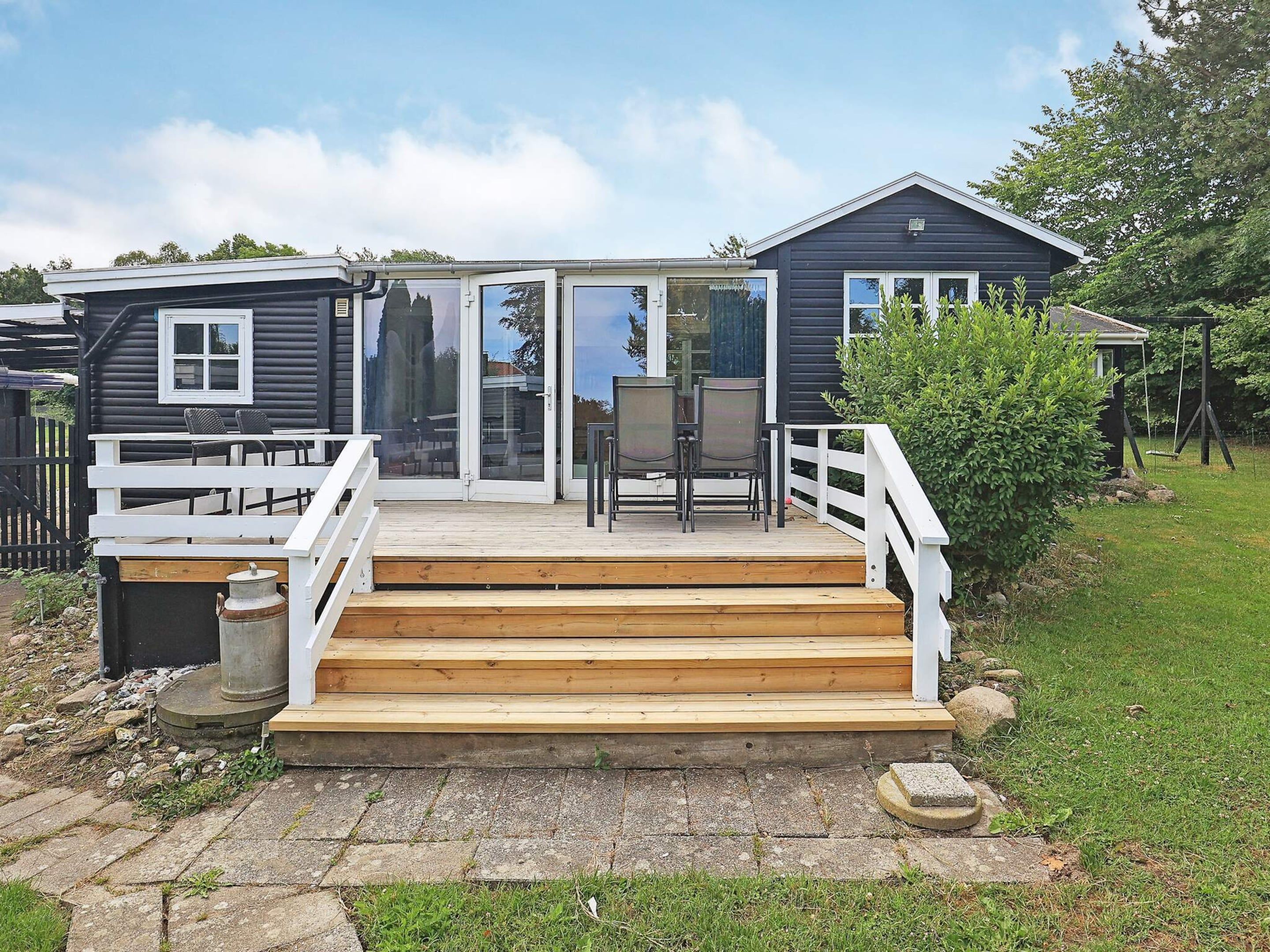 A two-story house with a deck, a sliding glass door, and a small outdoor seating area.