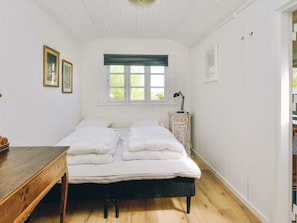 A bedroom with a bed, a desk, a lamp, and a window with curtains. - 8 Person Holiday Home in Holbaek (Holbaek)