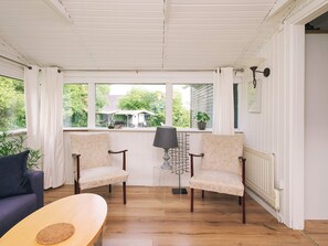 A sunroom with two chairs, a table, and a view of the outdoors. - 8 Person Holiday Home in Holbaek (Holbaek)