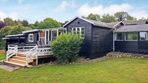 Een chalet met twee verdiepingen, een terras en een schoorsteen.