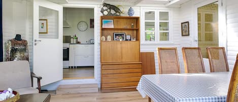 Une pièce comprenant un lit, une table à manger, des chaises, un buffet en bois, un coin cuisine et une salle de bain.