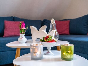 A cozy living area with a blue sofa, a white table with candles, a vase with flowers, and a decorative glass bottle. - Heidetraum in der Pension Heidetraum (Bispingen)