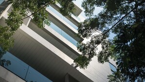 A modern building with multiple floors, large windows, and a view of the sky through the foliage. - Nice Residence Bangkok Sukhumvit (Bangkok)