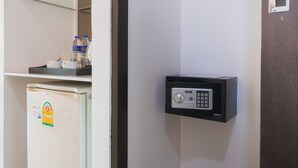 A refrigerator with a sticker, a Sure brand electronic keypad lock on a wall, and a shelf with bottles and a cup. - Nice Residence Bangkok Sukhumvit (Bangkok)