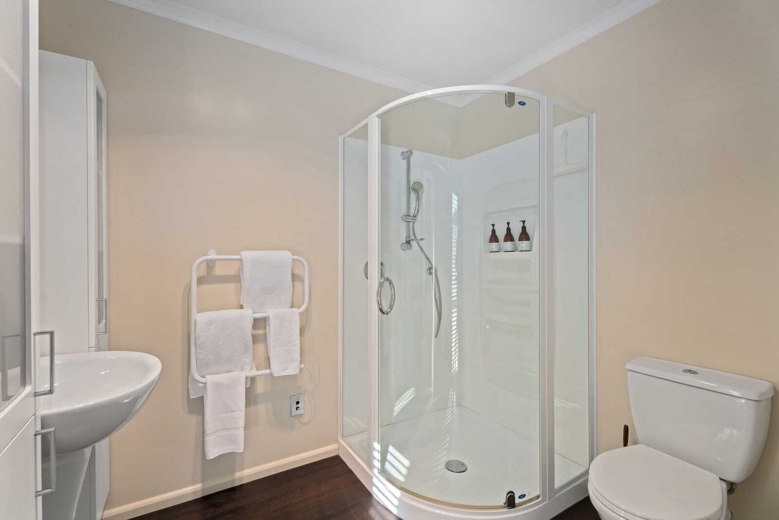 A modern bathroom with a glass-enclosed shower, a white sink, and a toilet.