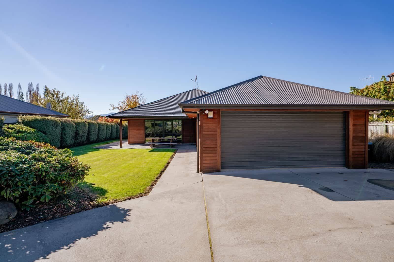 A modern house with a garage, a covered patio, and a well-maintained lawn.