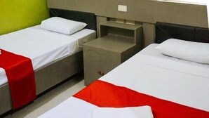 Une chambre d’hôtel avec deux lits simples, une petite table et une table de chevet.