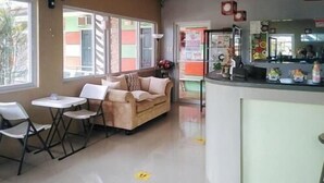 Une chambre d’hôtel équipée d’un canapé, de fauteuils, d’une petite table, d’un coin cuisine et d’une grande fenêtre.