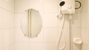 Une salle de bain avec un miroir rond, une douchette et des toilettes.