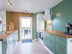 A modern kitchen with a wooden countertop, stainless steel appliances, and a view through a glass door. - 4 Star Holiday Home in Blavand (Blavand)