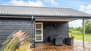 A modern house with a wooden deck and outdoor seating area.
