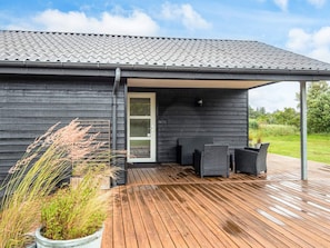 A modern house with a wooden deck and outdoor seating area. - 4 Star Holiday Home in Blavand (Blavand)