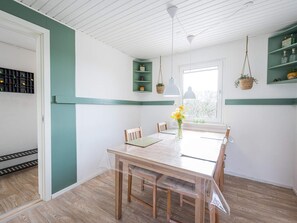 A dining area with a table, chairs, a vase with flowers, hanging lights, and a window with a view. - 4 Star Holiday Home in Blavand (Blavand)