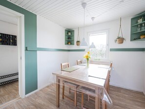 Un comedor con una mesa y sillas de madera, un florero con flores, y una ventana con vistas.