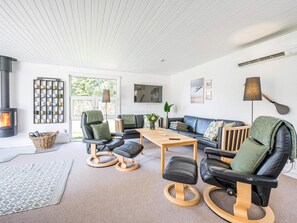 Una sala de estar moderna con chimenea, muebles de cuero, una mesa de café y vistas al exterior.