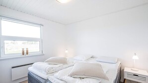 A bedroom with a bed, bedside tables, a window with a view, and a ceiling light.
