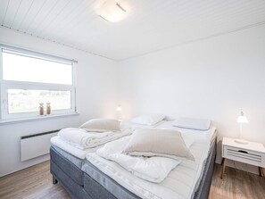 A bedroom with a bed, bedside tables, a window with a view, and a ceiling light. - 4 Star Holiday Home in Blavand (Blavand)