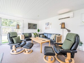 A modern living room with a sofa set, a coffee table, and a TV mounted on the wall. - 4 Star Holiday Home in Blavand (Blavand)